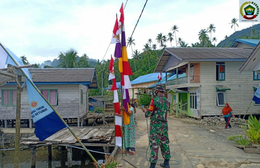 Jajaran Kodim 0318/Natuna, Melalui Babinsa Serda Irfansyah Koramil 03/Sedanau, Bantu Warga Pasang Bendera