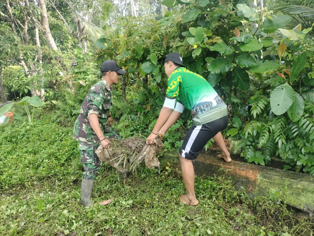 Kerap Dilanda Banjir Saat Hujan, Babinsa Bersama Warga Goro Bersihkan Drainase Lapangan Bola Kali